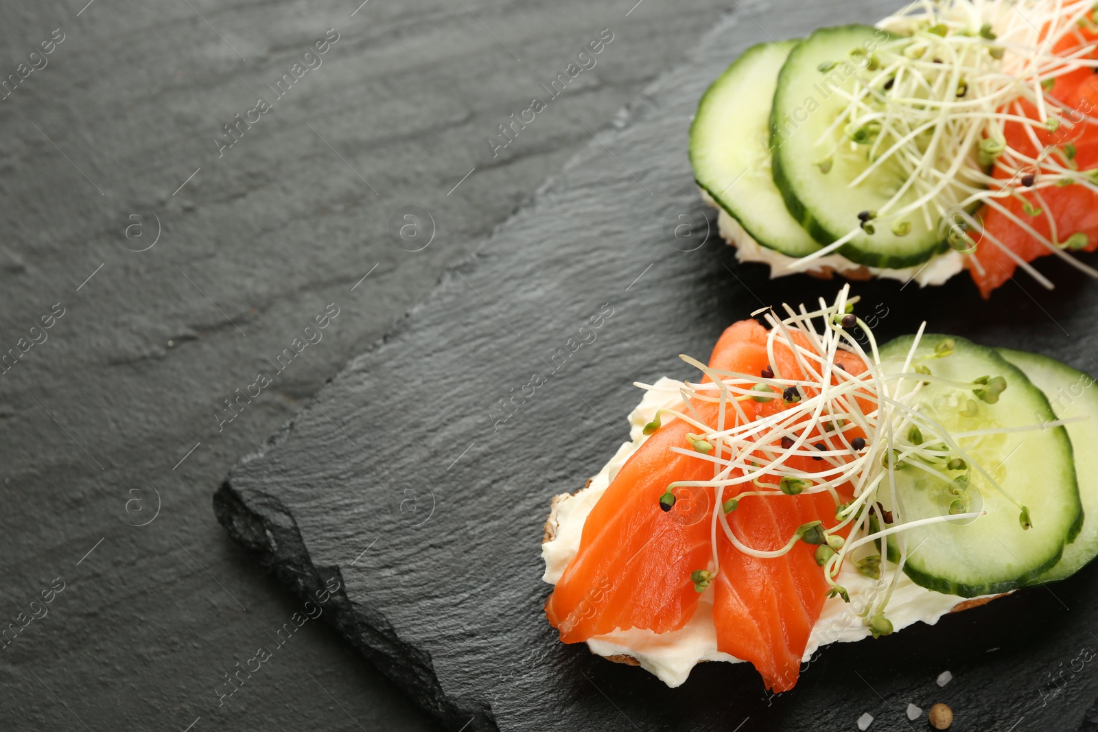 Photo of Delicious bruschette with salmon, cream cheese and cucumber on grey table, closeup. Space for text