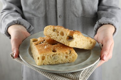 Photo of Woman with pieces of delicious focaccia bread on light background, closeup