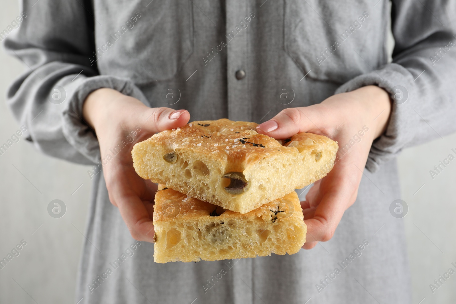 Photo of Woman with pieces of delicious focaccia bread on light background, closeup