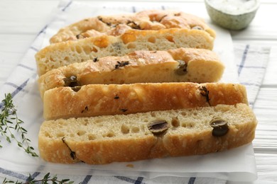 Photo of Slices of delicious focaccia bread with olives and thyme on table, closeup