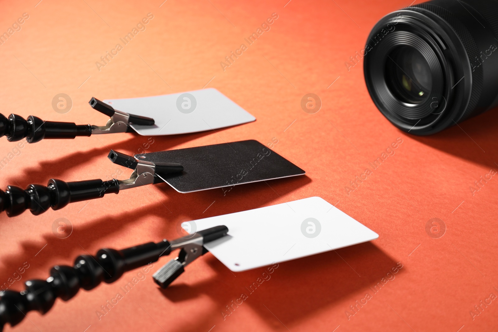 Photo of White balance calibration cards and camera on red background, closeup