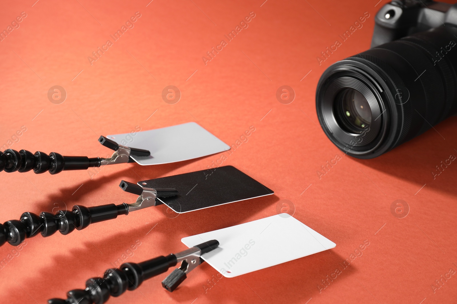 Photo of White balance calibration cards and camera on red background, closeup