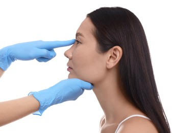 Photo of Doctor checking patient's nose before plastic surgery operation on white background, closeup