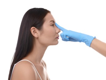 Photo of Doctor checking patient's nose before plastic surgery operation on white background, closeup