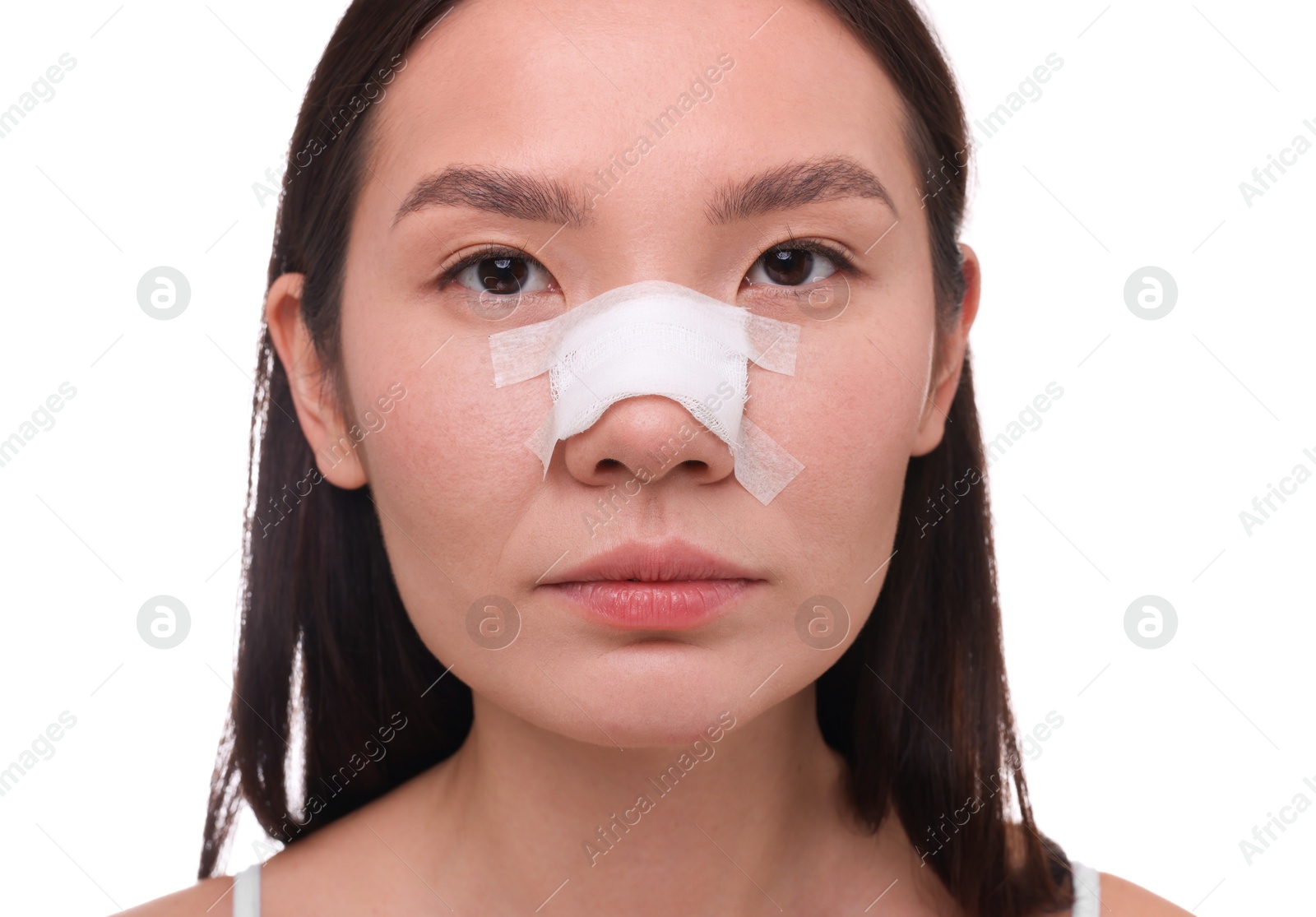 Photo of Woman with medical bandage on her nose after plastic surgery operation against white background, closeup