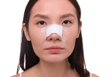 Photo of Woman with medical bandage on her nose after plastic surgery operation against white background, closeup