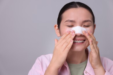 Photo of Woman with medical bandage on her nose after plastic surgery operation against light grey background