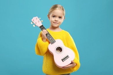 Photo of Little girl with ukulele on light blue background