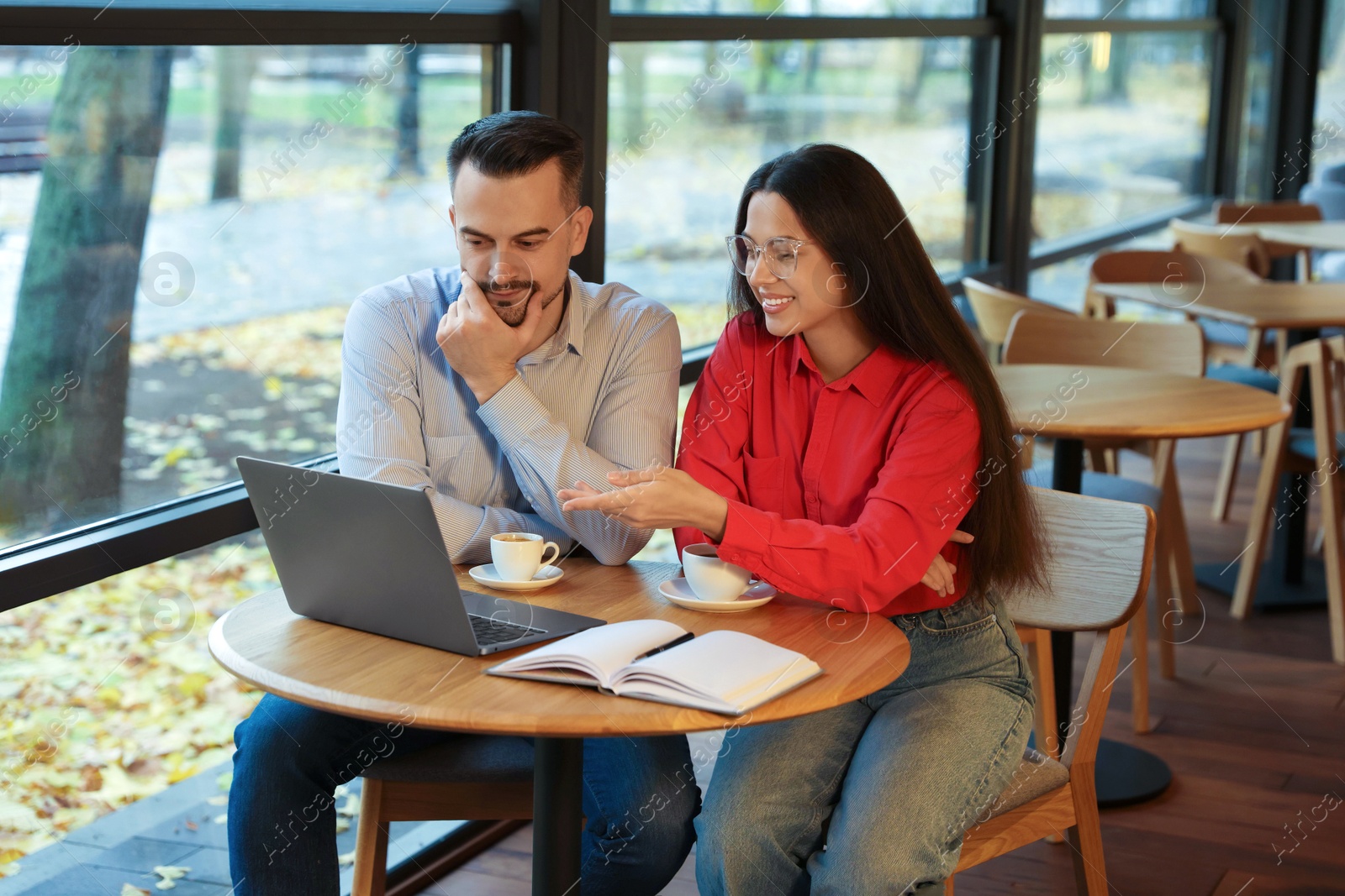 Photo of Colleagues with laptop working together in cafe