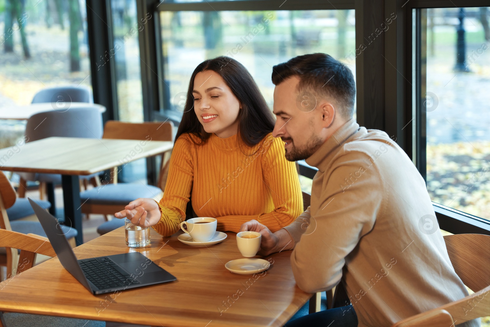 Photo of Colleagues with laptop working together at table in cafe