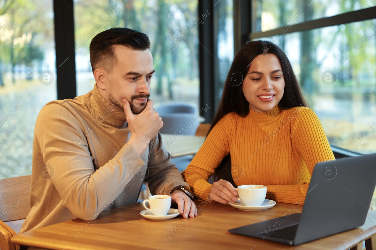 Photo of Colleagues with laptop working together at table in cafe