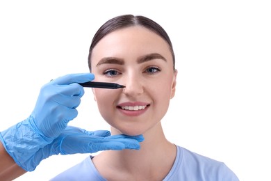 Photo of Doctor drawing marks on patient's nose for plastic surgery operation against white background, closeup