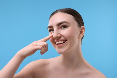 Photo of Woman touching her nose on light blue background