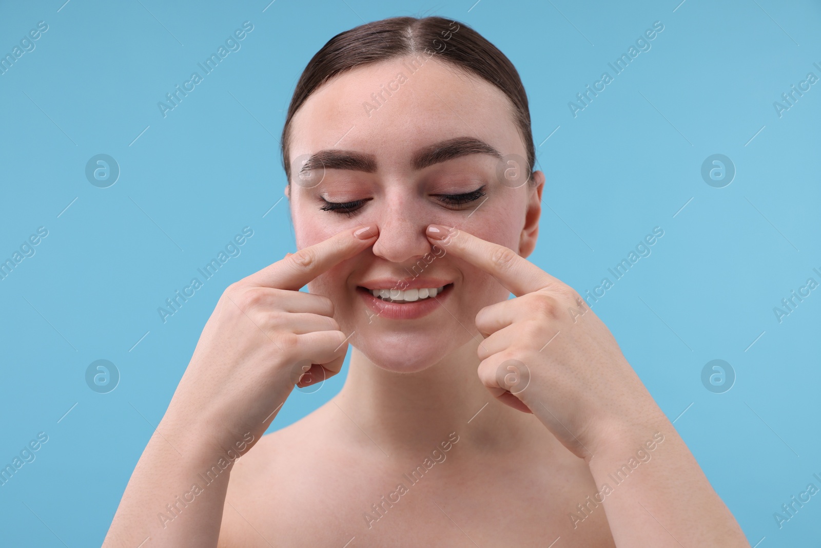 Photo of Woman touching her nose on light blue background