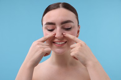 Photo of Woman touching her nose on light blue background