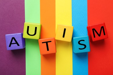 Photo of Word Autism made with colorful cubes on color background, flat lay