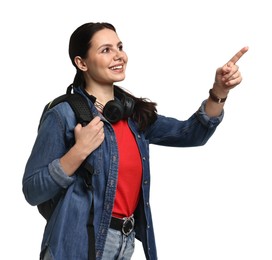 Photo of Young tourist with backpack and headphones pointing at something on white background