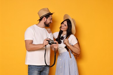 Photo of Tourism. Happy couple in hats with camera on yellow background