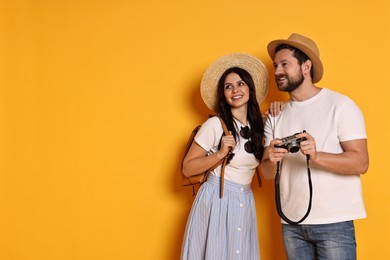 Photo of Tourism. Happy couple in hats with camera on yellow background, space for text