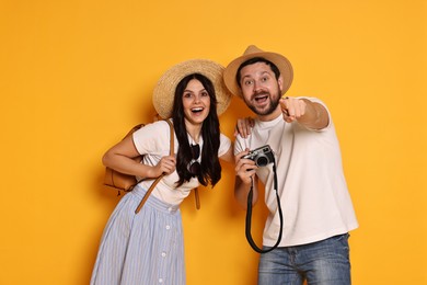 Photo of Tourism. Emotional couple in hats with camera on yellow background