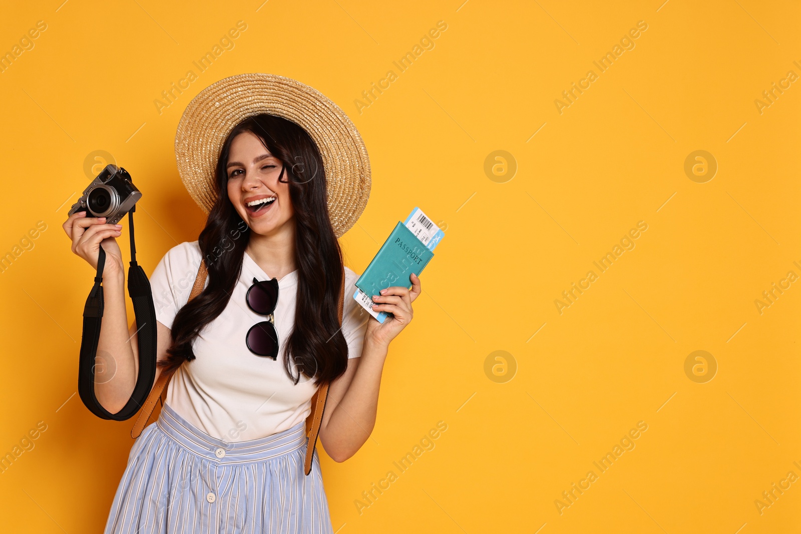 Photo of Young tourist in hat with camera, passport and ticket on yellow background, space for text