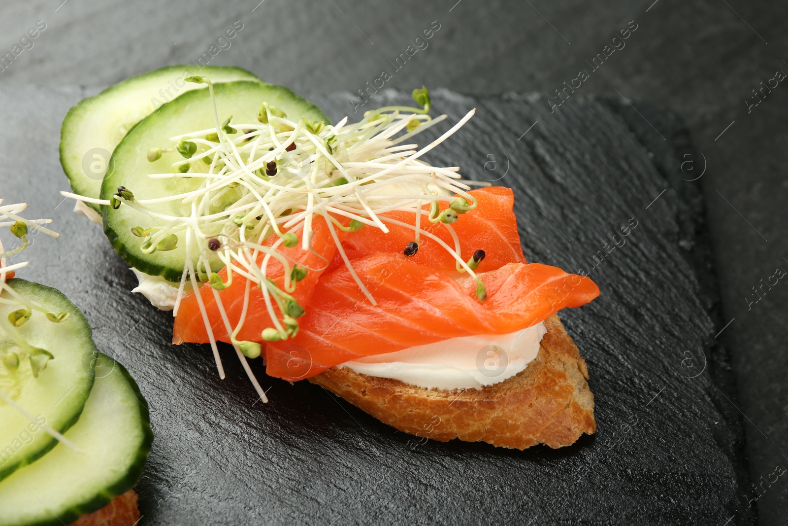 Photo of Delicious bruschette with salmon, cream cheese and cucumber on grey table, closeup