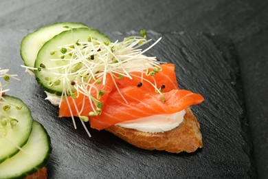 Photo of Delicious bruschette with salmon, cream cheese and cucumber on grey table, closeup