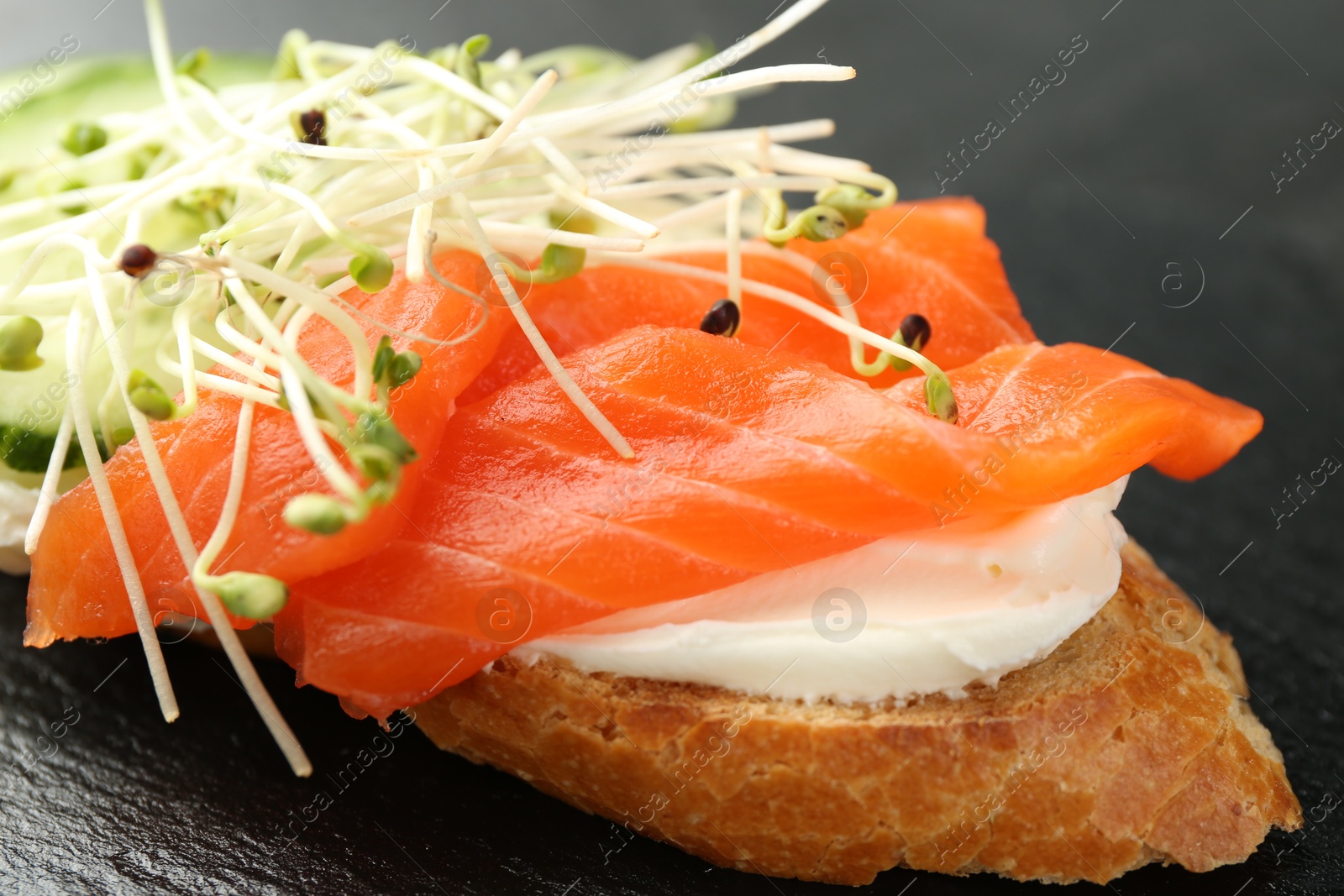 Photo of Delicious bruschetta with salmon, cream cheese and cucumber on grey table, closeup