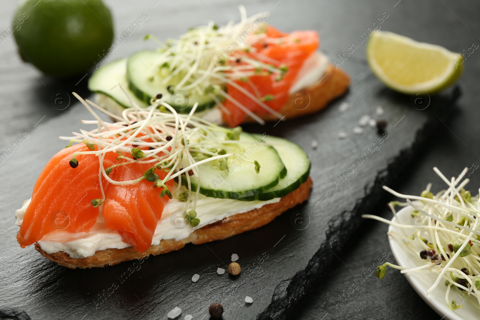 Photo of Delicious bruschette with salmon, cream cheese and cucumber on grey table, closeup