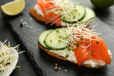 Photo of Delicious bruschette with salmon, cream cheese and cucumber on grey table, closeup