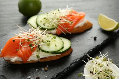 Photo of Delicious bruschette with salmon, cream cheese and cucumber on grey table, closeup