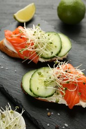 Photo of Delicious bruschette with salmon, cream cheese and cucumber on grey table, closeup