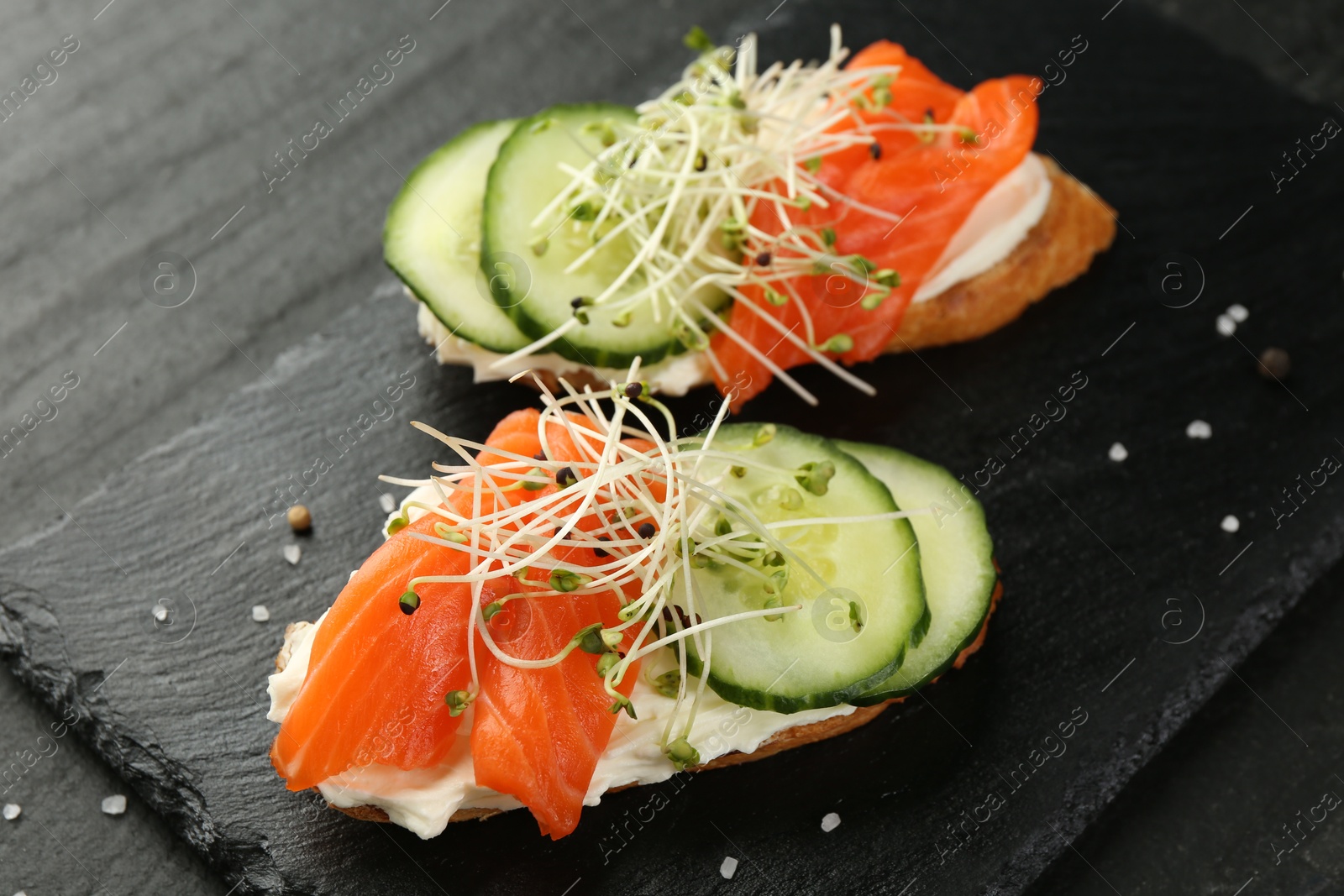 Photo of Delicious bruschette with salmon, cream cheese and cucumber on grey table, closeup