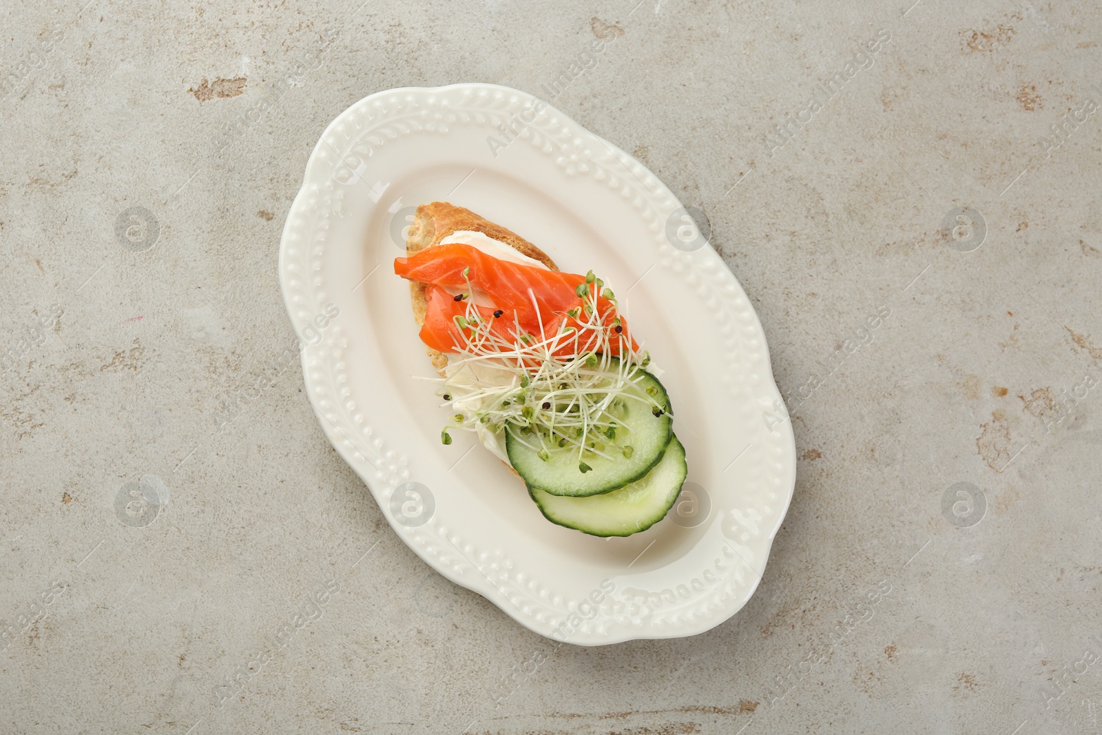 Photo of Delicious bruschetta with salmon, cream cheese and cucumber on light table, top view