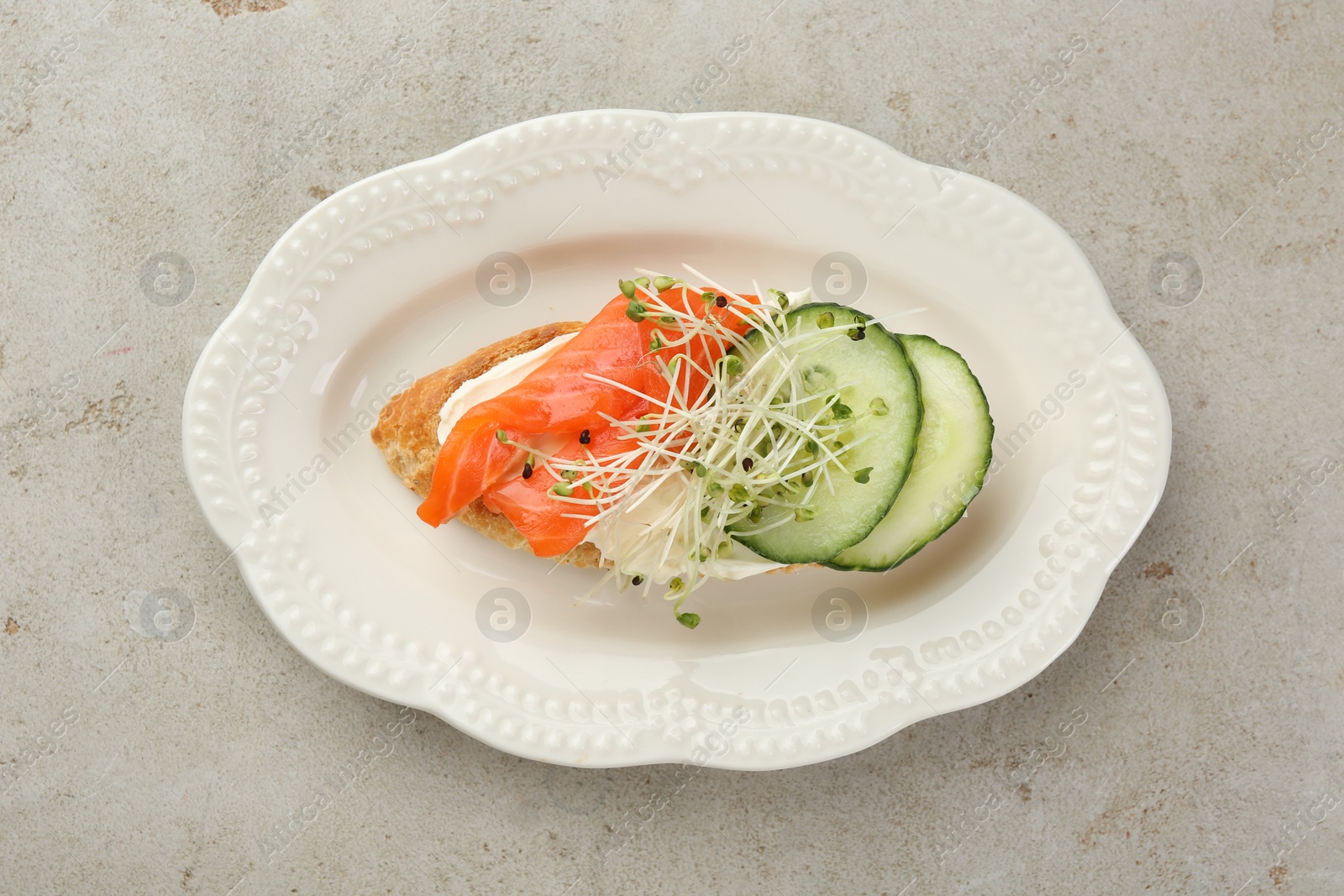 Photo of Delicious bruschetta with salmon, cream cheese and cucumber on light table, top view