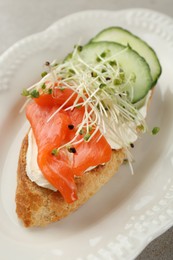 Photo of Delicious bruschetta with salmon, cream cheese and cucumber on light table, closeup