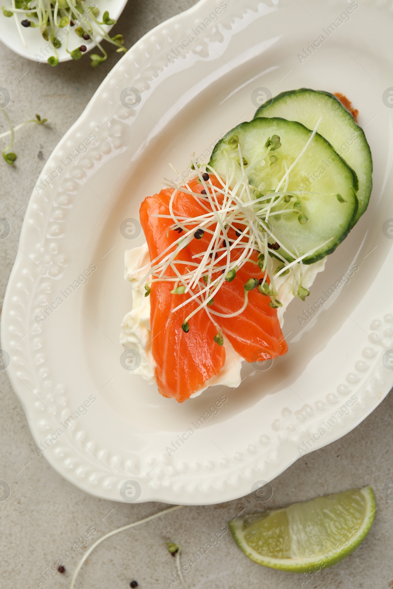 Photo of Delicious bruschetta with salmon, cream cheese and cucumber on light table, top view