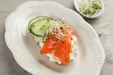 Photo of Delicious bruschetta with salmon, cream cheese and cucumber on light table, closeup