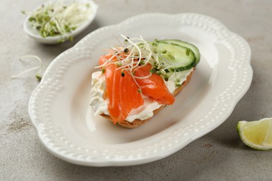 Photo of Delicious bruschetta with salmon, cream cheese and cucumber on light table, closeup