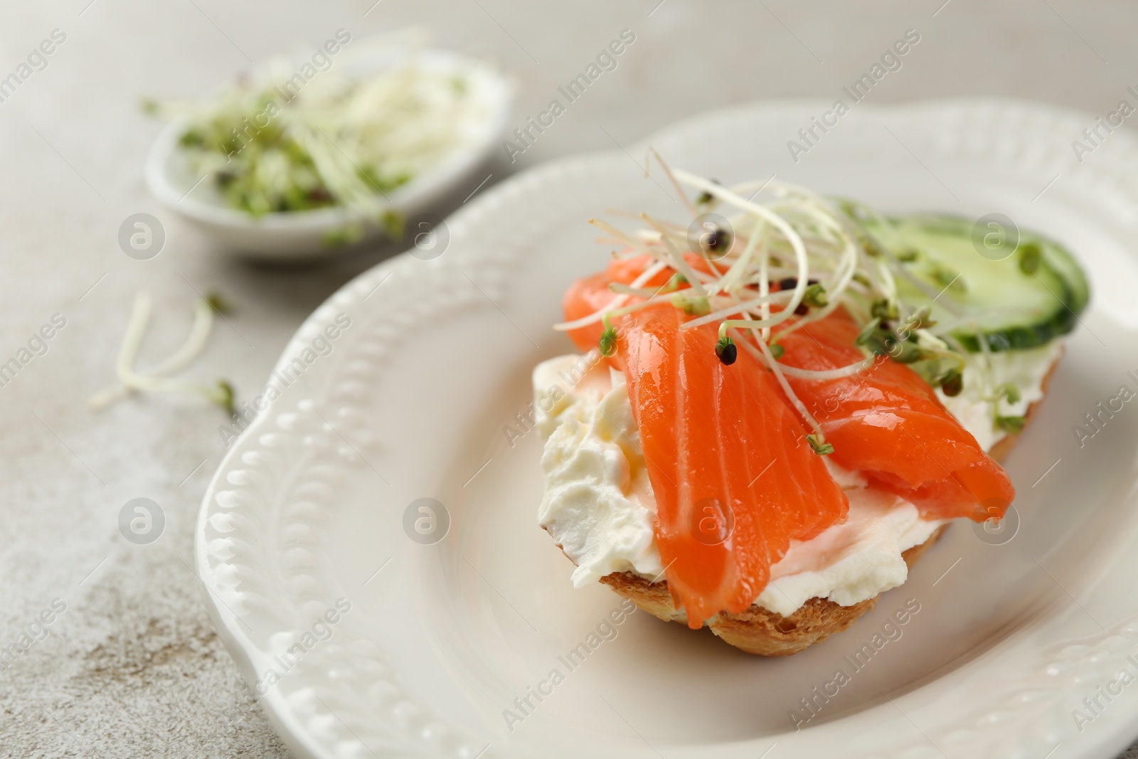 Photo of Delicious bruschetta with salmon, cream cheese and cucumber on light table, closeup