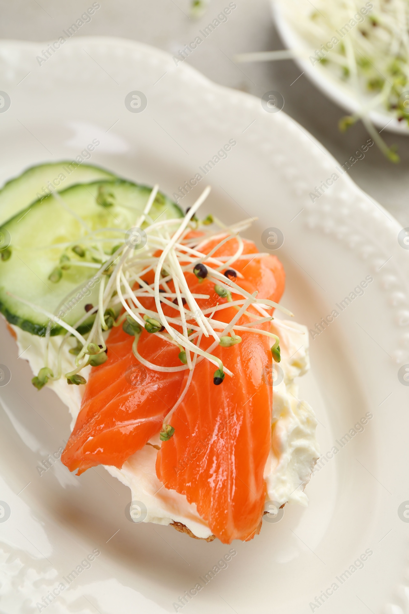 Photo of Delicious bruschetta with salmon, cream cheese and cucumber on light table, closeup