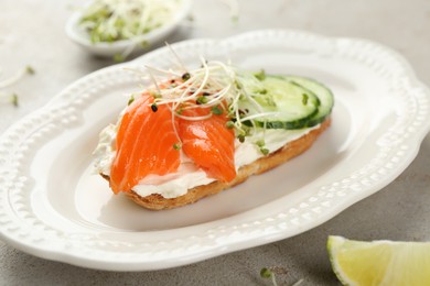 Photo of Delicious bruschetta with salmon, cream cheese and cucumber on light table, closeup