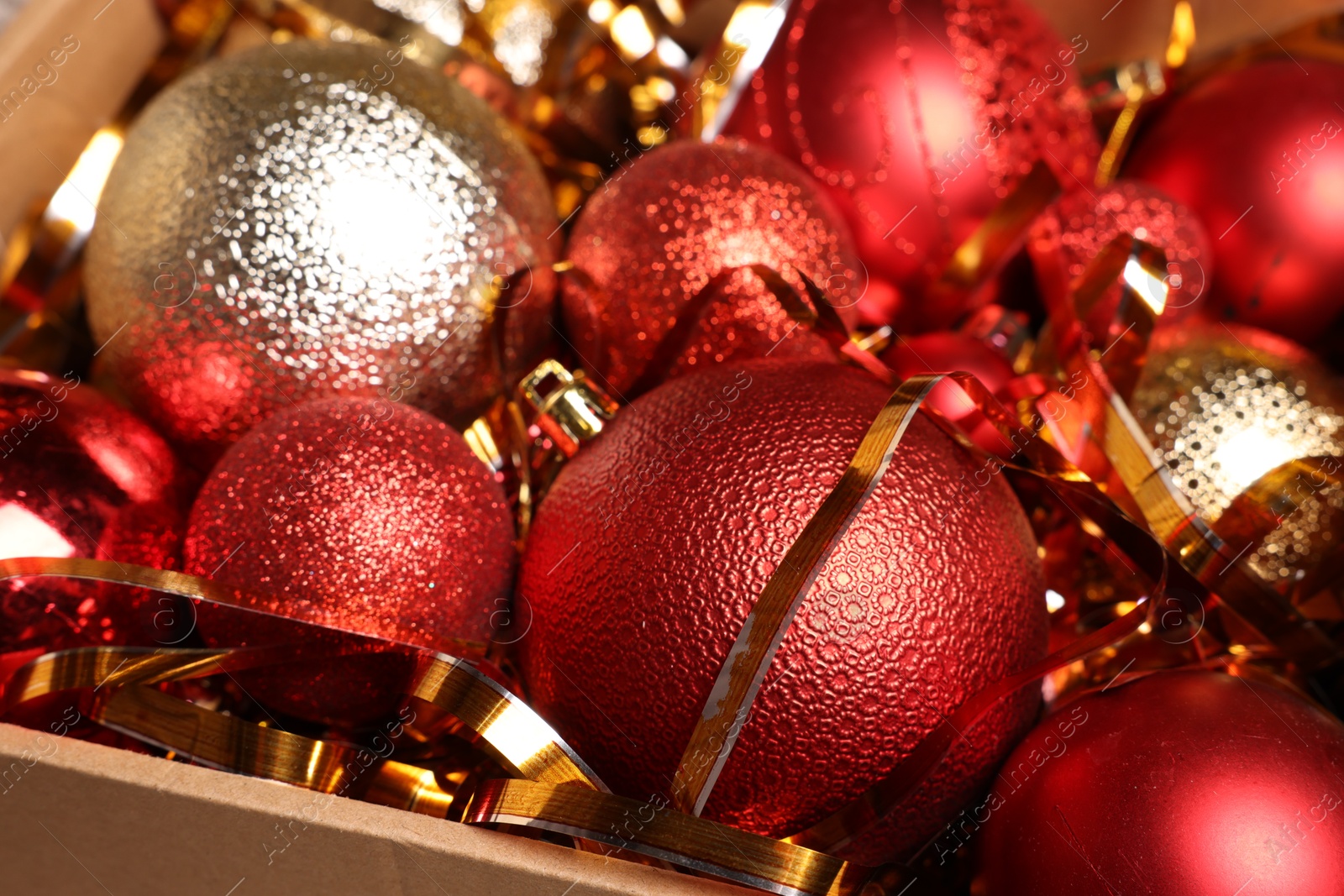 Photo of Shiny tinsel and Christmas balls in cardboard box, closeup