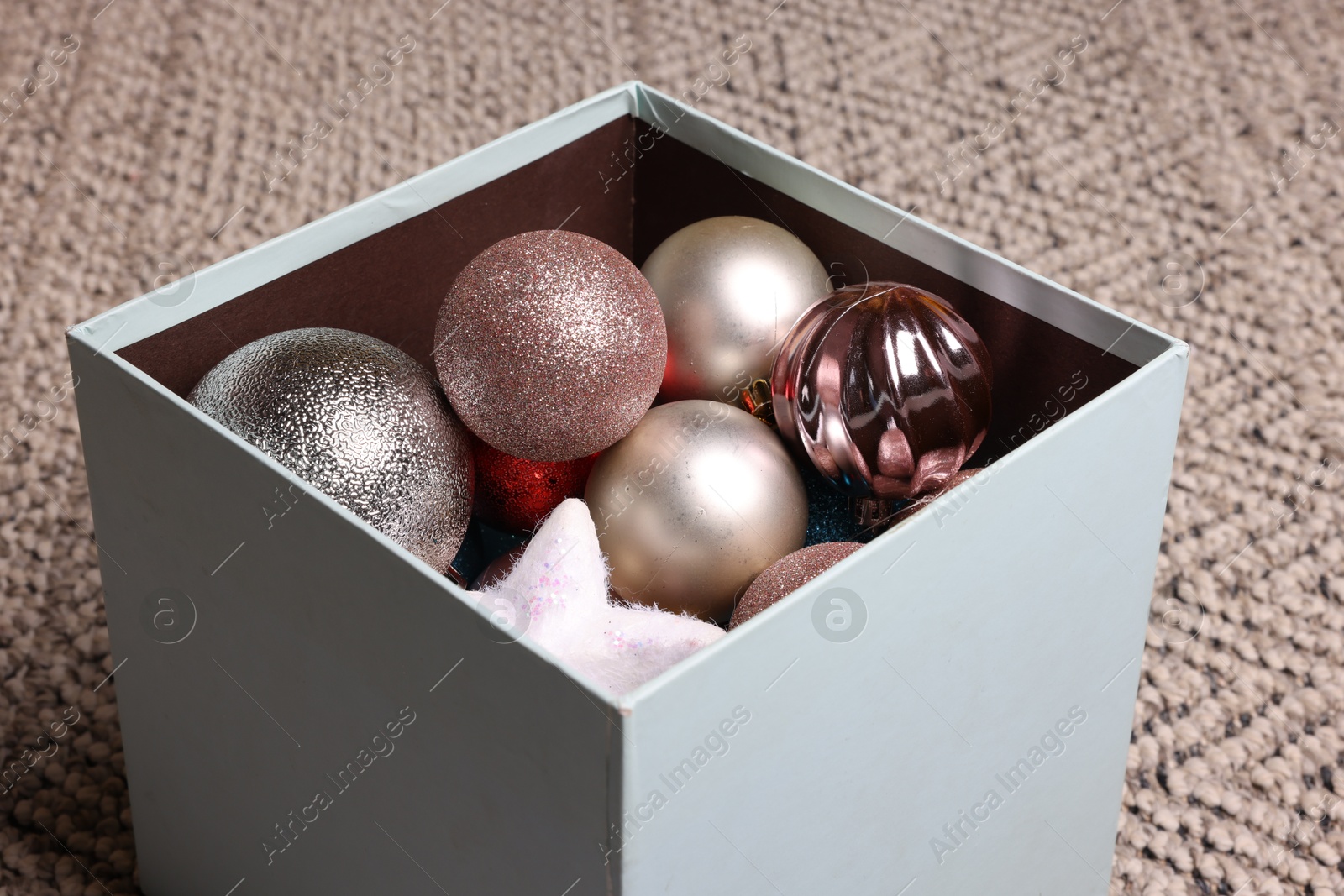 Photo of Different Christmas decor in box on carpet, closeup