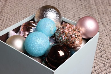 Photo of Different Christmas decor in box on carpet, closeup