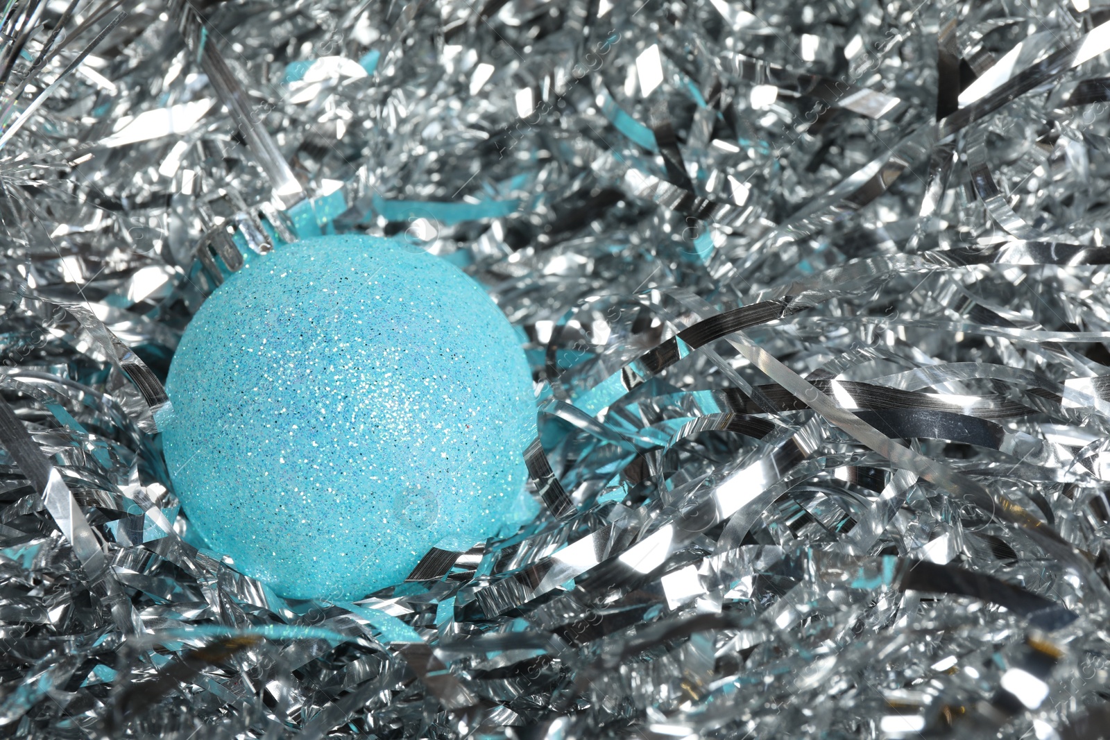 Photo of Beautiful Christmas ball on shiny tinsel, closeup. Space for text