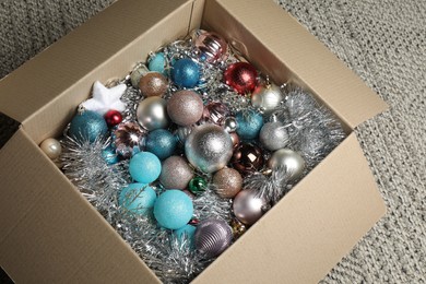 Photo of Different Christmas decor in cardboard box on carpet indoors