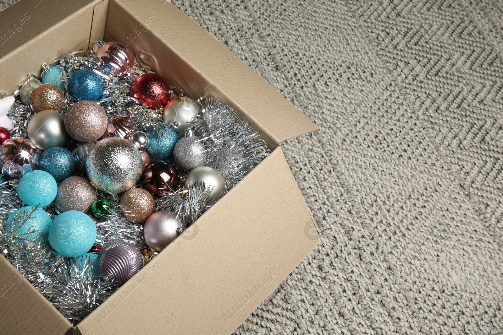 Photo of Different Christmas decor in cardboard box on carpet, space for text