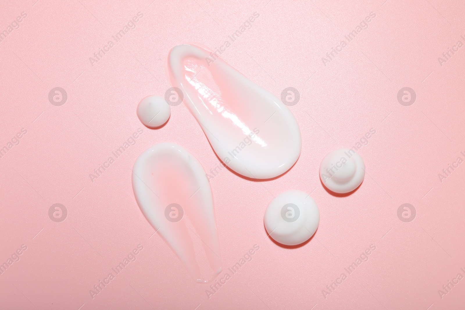 Photo of Cream samples on pink background, top view. Skincare product