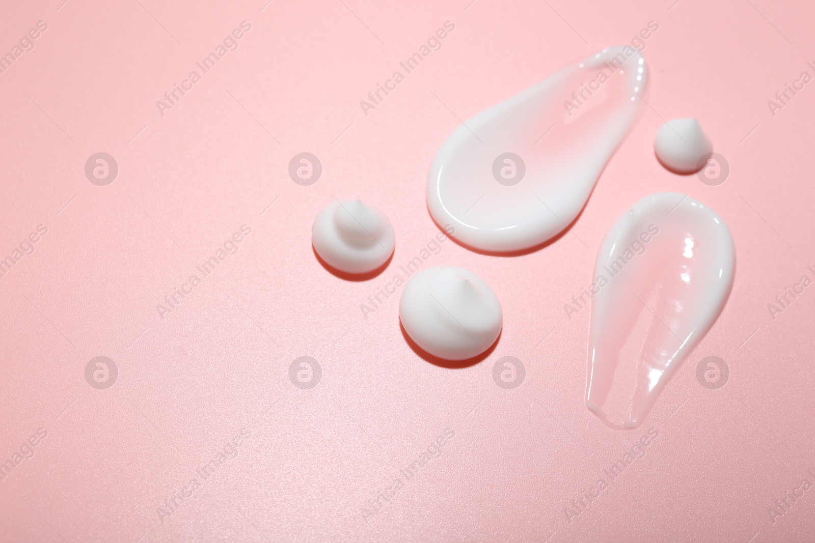 Photo of Cream samples on pink background, space for text. Skincare product